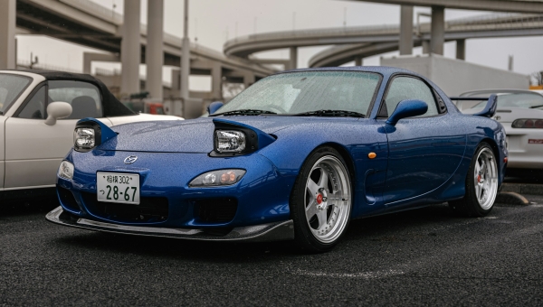 Prednji deo plave Mazde RX-7 FD sa otvorenim pop-up svetlima parkirane na skupu u Japanu